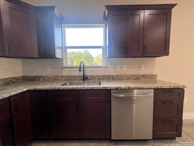 kitchen with light stone counters, sink, dark brown cabinetry, and stainless steel dishwasher