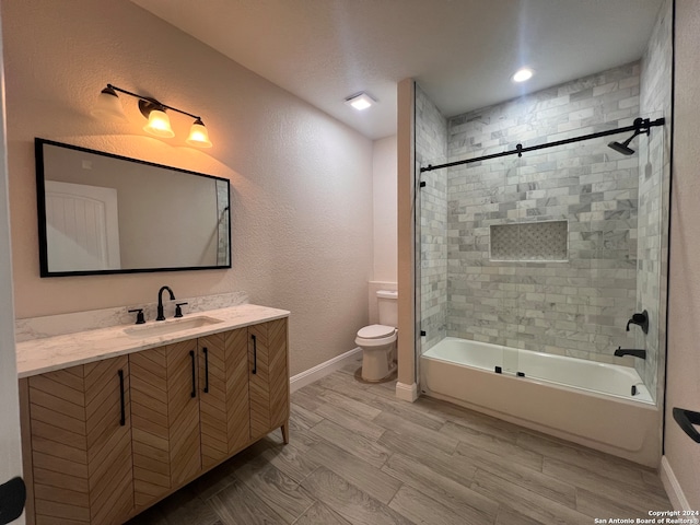 full bathroom with tiled shower / bath, toilet, hardwood / wood-style flooring, and vanity