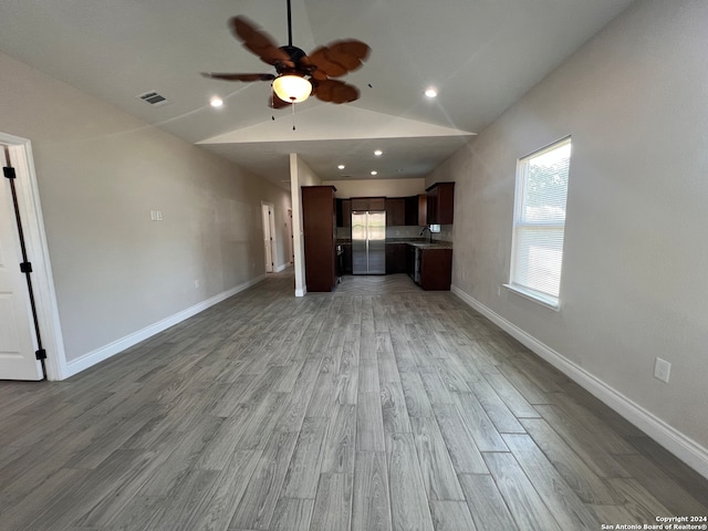 unfurnished living room featuring lofted ceiling, wood-type flooring, sink, and ceiling fan