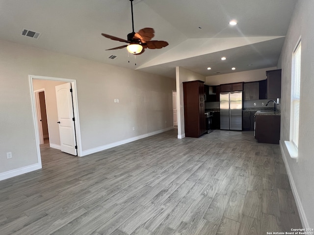 unfurnished living room featuring lofted ceiling, hardwood / wood-style floors, sink, and ceiling fan