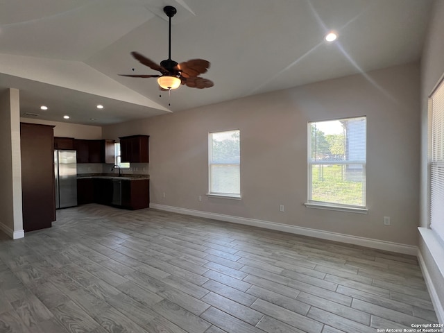 unfurnished living room featuring ceiling fan, sink, light wood-type flooring, and vaulted ceiling