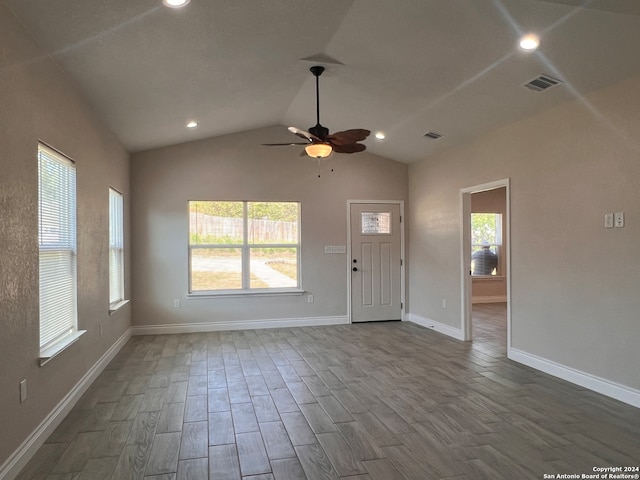 unfurnished living room with vaulted ceiling, dark hardwood / wood-style flooring, a wealth of natural light, and ceiling fan