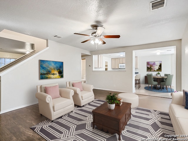 living room with a textured ceiling, hardwood / wood-style floors, and ceiling fan