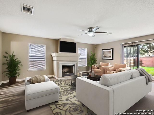 living room with a textured ceiling, ceiling fan, and wood-type flooring