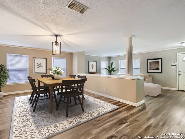 dining room featuring a textured ceiling, dark wood-type flooring, and ornamental molding