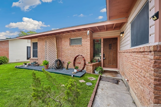 property entrance featuring brick siding and a yard