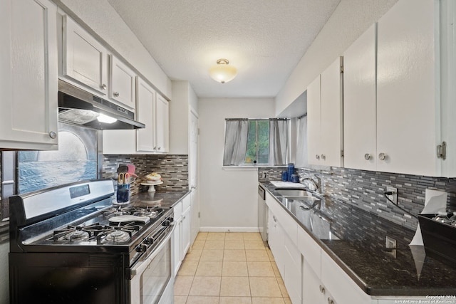 kitchen with sink, light tile patterned flooring, appliances with stainless steel finishes, white cabinets, and dark stone counters