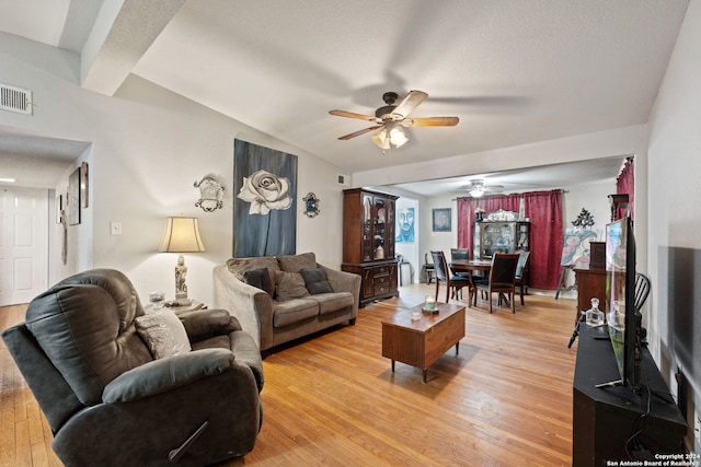 living room featuring ceiling fan, beamed ceiling, a textured ceiling, and hardwood / wood-style floors