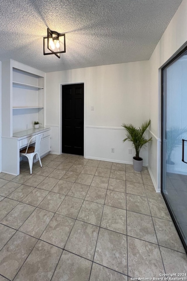 tiled empty room with a textured ceiling