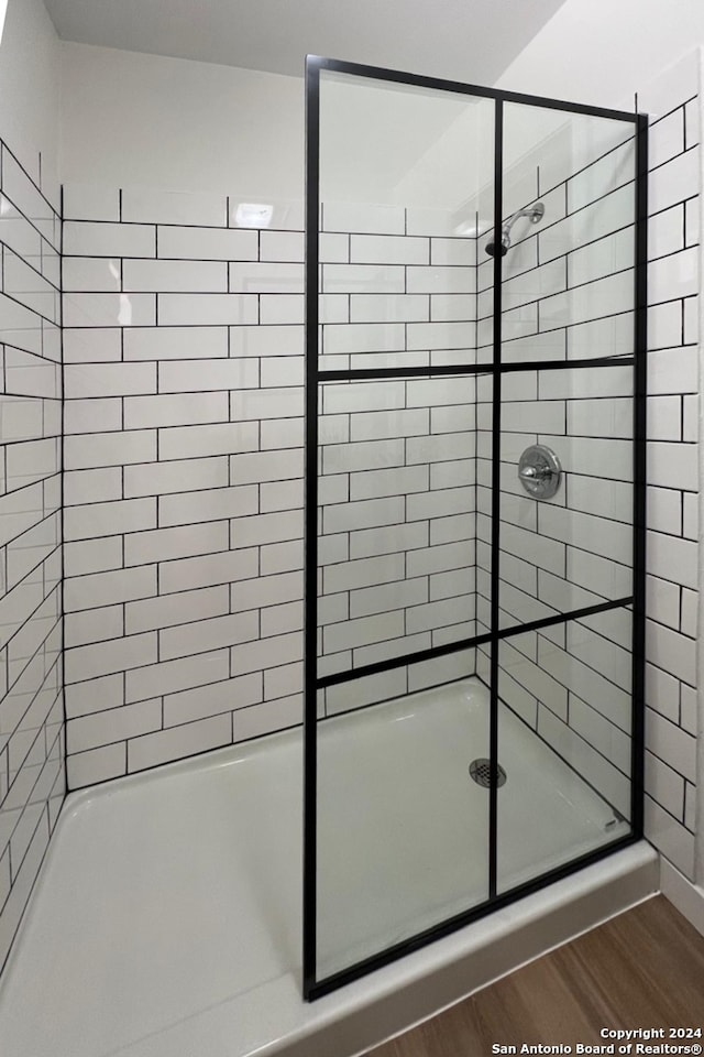 bathroom with a shower with door and hardwood / wood-style floors