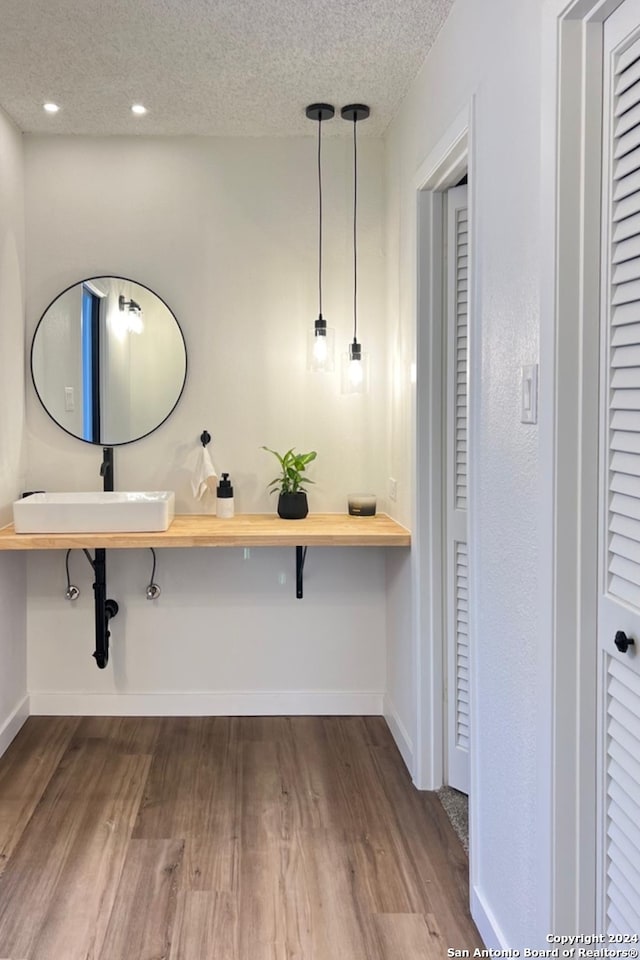 bathroom with a textured ceiling, wood-type flooring, and sink