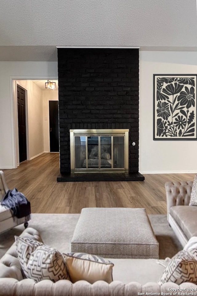 living room with a textured ceiling, hardwood / wood-style floors, and a fireplace