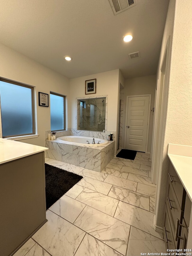 bathroom with vanity and a relaxing tiled tub