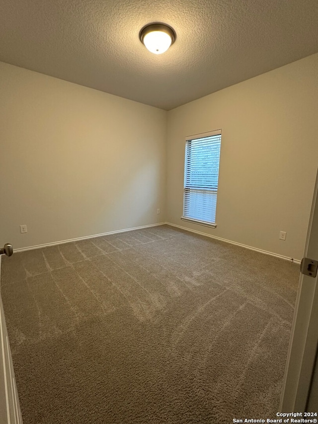 carpeted spare room featuring a textured ceiling