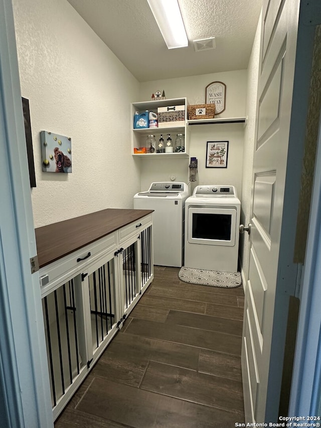 washroom featuring dark wood-type flooring, washing machine and dryer, and a textured ceiling