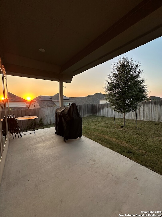 patio terrace at dusk featuring a yard and area for grilling