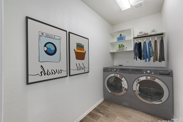 laundry room featuring baseboards, visible vents, wood tiled floor, laundry area, and washing machine and dryer