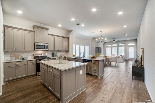 kitchen featuring a peninsula, a sink, gray cabinetry, appliances with stainless steel finishes, and a center island