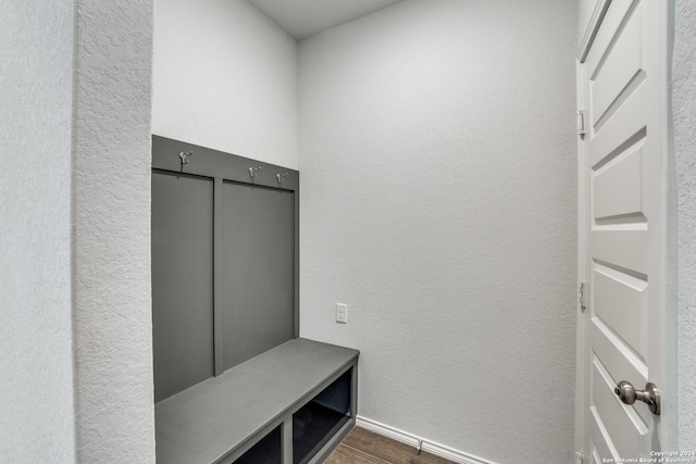 mudroom featuring baseboards, dark wood-type flooring, and a textured wall