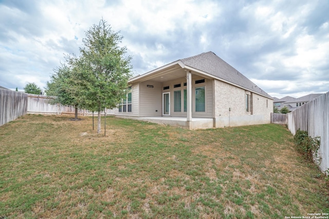 rear view of house with a patio area, a lawn, and a fenced backyard