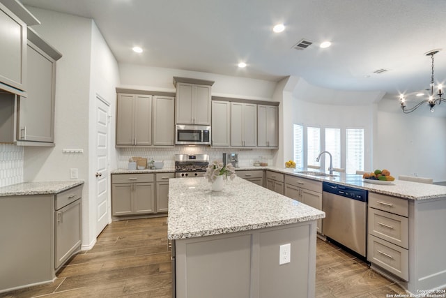 kitchen with visible vents, a peninsula, gray cabinets, a sink, and stainless steel appliances