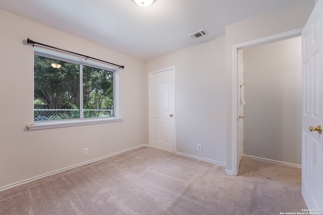 unfurnished bedroom featuring a closet and light carpet