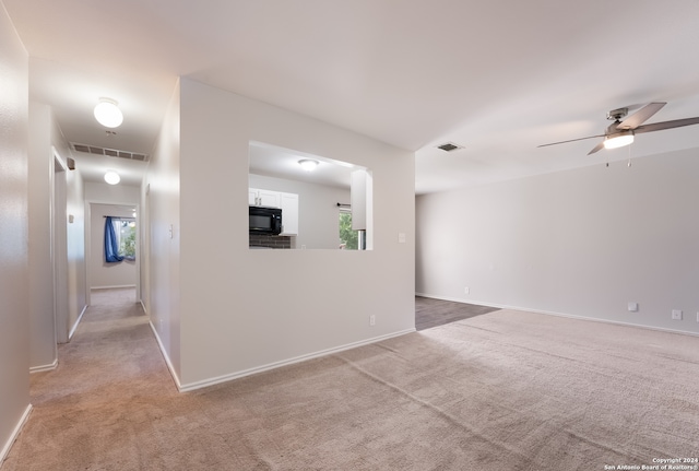 empty room with light colored carpet, a healthy amount of sunlight, and ceiling fan