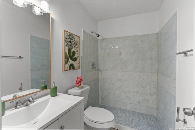 bathroom with a tile shower, vanity, a textured ceiling, and toilet