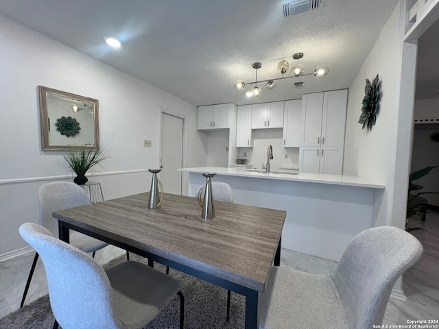 dining space featuring light hardwood / wood-style floors, a textured ceiling, and sink