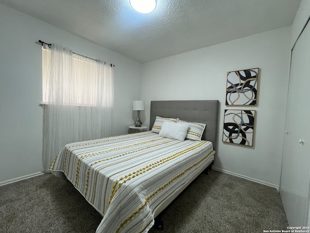 bedroom featuring a closet, a textured ceiling, and dark colored carpet