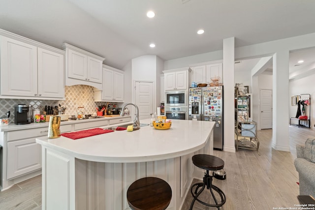 kitchen featuring stainless steel appliances, a center island with sink, white cabinetry, and sink