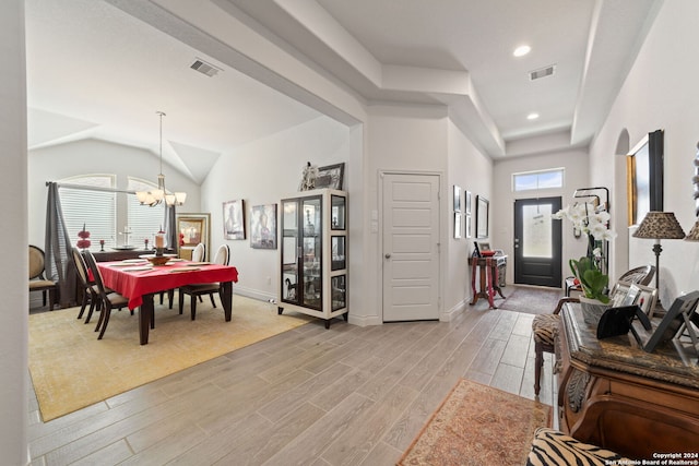 entrance foyer with vaulted ceiling, a notable chandelier, and light hardwood / wood-style floors