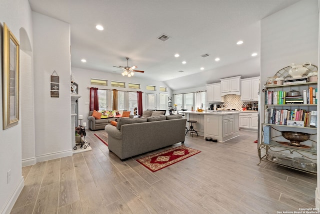 living room with light wood-type flooring, vaulted ceiling, and ceiling fan