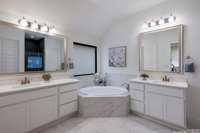 bathroom featuring vanity, tiled tub, and vaulted ceiling