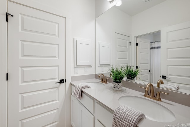 bathroom featuring visible vents, a sink, and double vanity