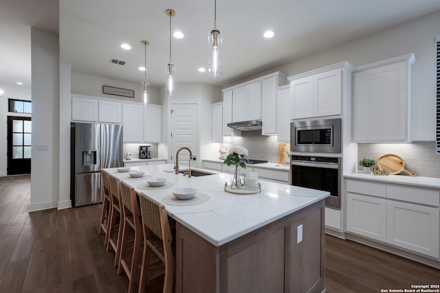 kitchen with dark hardwood / wood-style floors, a center island with sink, appliances with stainless steel finishes, sink, and white cabinetry