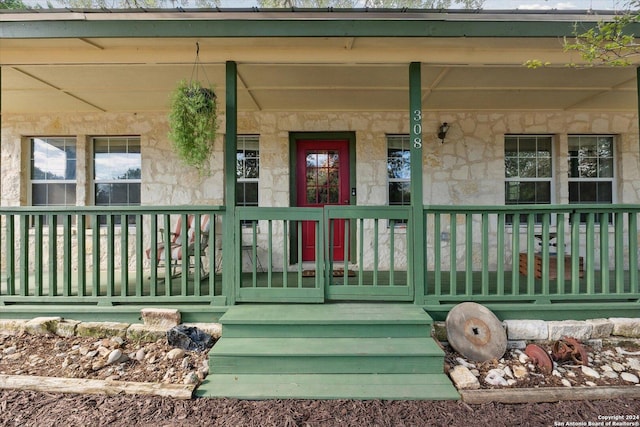 doorway to property with stone siding and covered porch