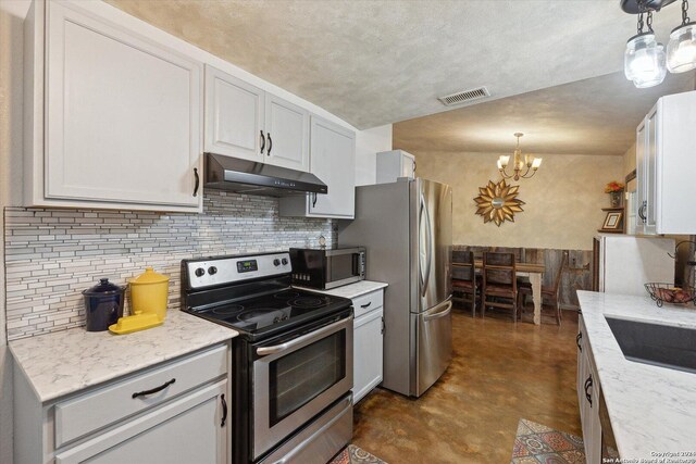 kitchen featuring hanging light fixtures, light stone countertops, appliances with stainless steel finishes, and a chandelier