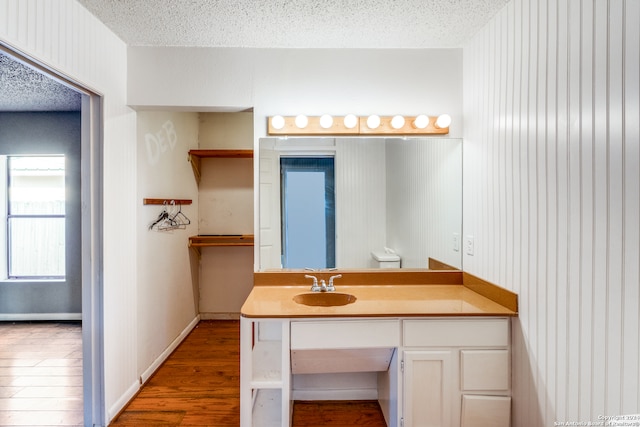 bathroom with hardwood / wood-style floors, a textured ceiling, and vanity