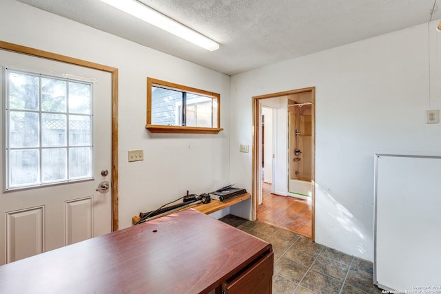 office area with a textured ceiling, plenty of natural light, and dark hardwood / wood-style floors