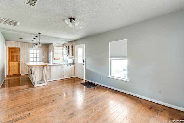 unfurnished living room featuring a textured ceiling and hardwood / wood-style floors