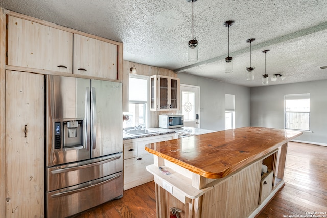 kitchen featuring dark hardwood / wood-style flooring, appliances with stainless steel finishes, a center island, sink, and wooden counters