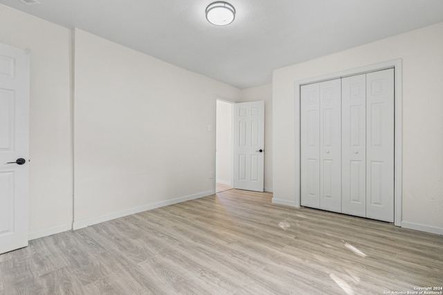 unfurnished bedroom with a closet and light hardwood / wood-style floors