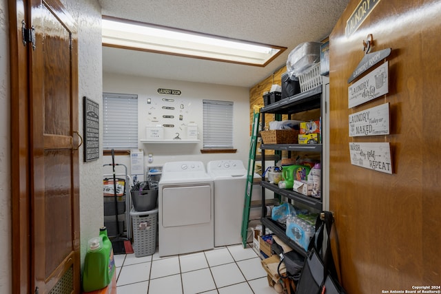 laundry room with a textured ceiling, light tile patterned flooring, and washing machine and clothes dryer