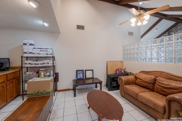 living room featuring ceiling fan, light tile patterned flooring, lofted ceiling with beams, and a textured ceiling