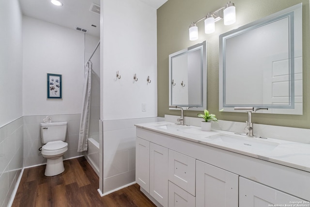 full bathroom with hardwood / wood-style flooring, toilet, tile walls, shower / tub combo, and vanity