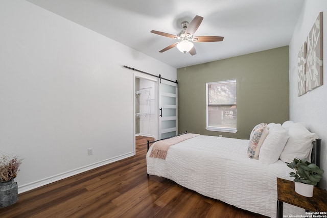 bedroom featuring a barn door, ceiling fan, dark hardwood / wood-style floors, and a closet