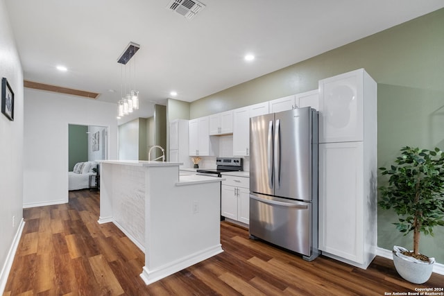 kitchen featuring white cabinets, decorative light fixtures, appliances with stainless steel finishes, dark hardwood / wood-style flooring, and an island with sink