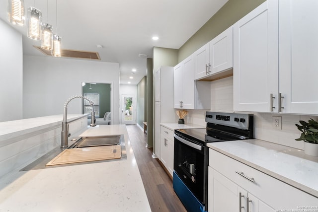 kitchen with dark wood-type flooring, stainless steel electric range oven, white cabinets, and hanging light fixtures