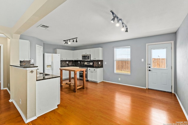 kitchen with light wood-type flooring, visible vents, dark countertops, white cabinetry, and appliances with stainless steel finishes